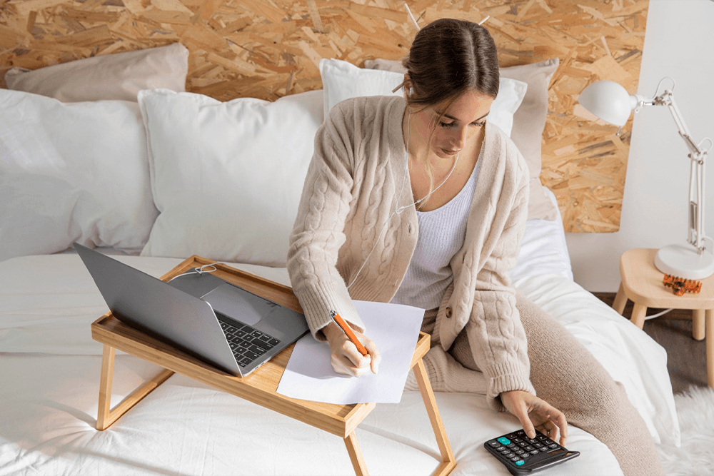 Mujer con computador y calculadora sacando cuentas
