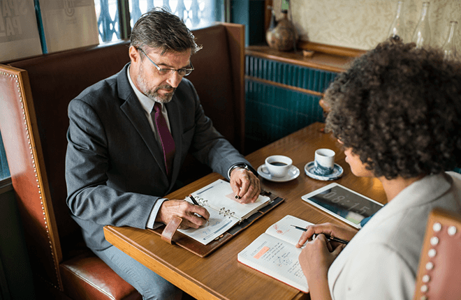 Abogado y cliente sentados en un establecimiento comercial