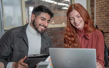 Mujer y hombre jovenes utilizando computador portatil