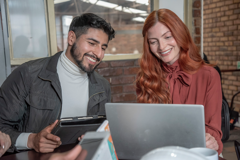 Hombre y mujer jovenes mirando laptop