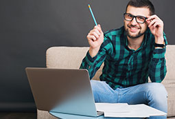 Hombre frente a un computador sosteniendo un lápiz