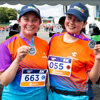 dos mujeres sonriendo mostrando sus medallas de la carrera 