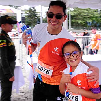Hombre y niña competidores de la carrera atlética sonriendo mostrando sus medallas