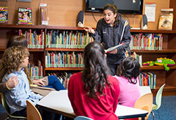 Mujer enseñándole a un grupo de niños en una biblioteca