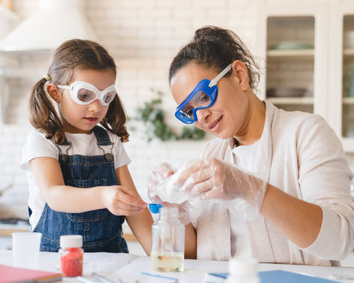 Mamá e hija con gafas de protección haciendo experimentos.