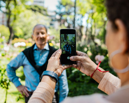 imagen de Mujer adulta tomando una foto con su celular a un adulto mayor.