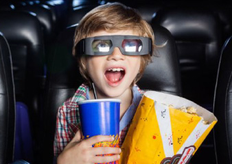 Niño viendo pelicula con comida y bebida en cine