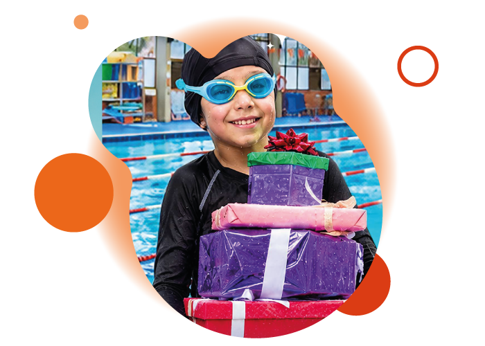 niño feliz con traje de natación y cargando cajas de regalos