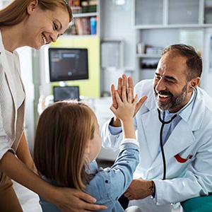 Medico en su consultorio chocando las manos de forma amistosa con un niño 