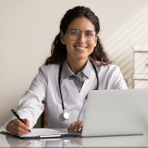 Mujer médico sonriente frente a su computador 