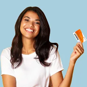 Mujer sonriendo y mostrando una tarjeta de Compensar 