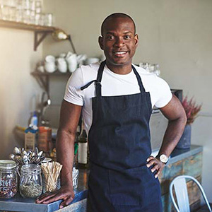 Hombre de raza negra sonriente, vestido con delantal en una cocina 
