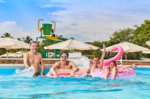 Familia feliz en la piscina con los flotadores