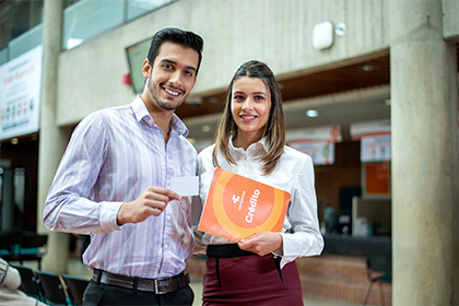 Hombre y mujer jóvenes con catálogo de crédito Compensar, Líneas de crédito compensar