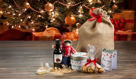 Vino, galles, dulces y canasta sobre mesa y árbol navideño