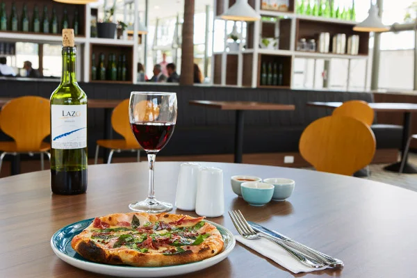 Mesa de restaurante italiano con una pizza personal y una copa de vino