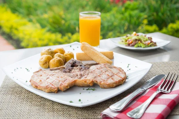 Imagen de una mesa con un exquisito almuerzo y de fondo las zonas verdes de la sede campestre de Cajicá