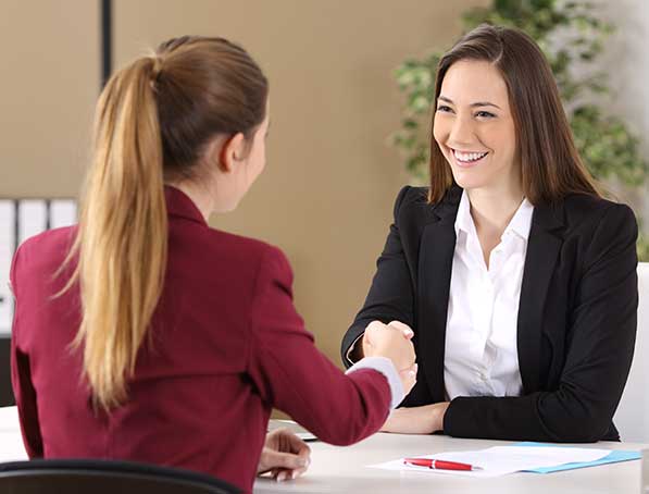 dos mujeres en oficina dandose la mano