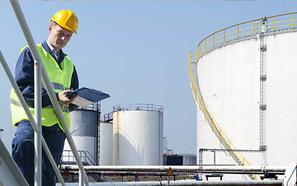 imagen de un hombre con casco y chaleco, de fondo infraestructura industrial 