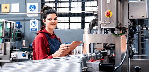 Mujer joven sonriendo y mirando una plantilla en una fábrica.