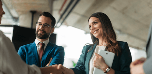 Mujer y hombre ejecutivos estrechando las manos en señal de cierre de negocios.