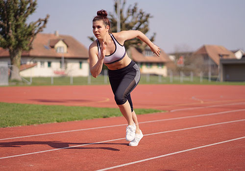 mujer corriendo en una pista de atletismo