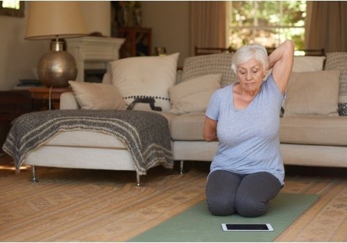 mujer anciana realizando yoga y estiramento en su sala