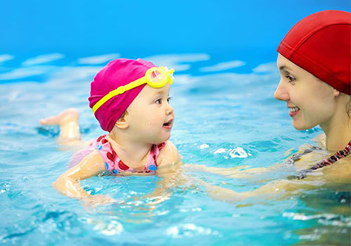 madre con su hija nadando en una piscina