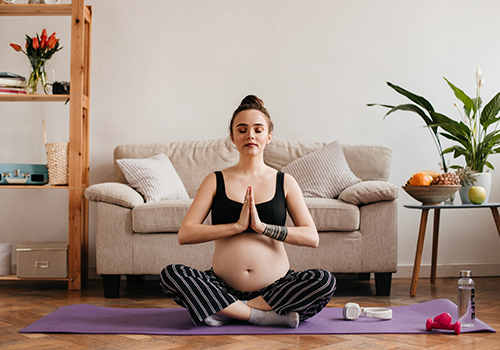 mujer embarazada haciendo yoga tocandose el estomago