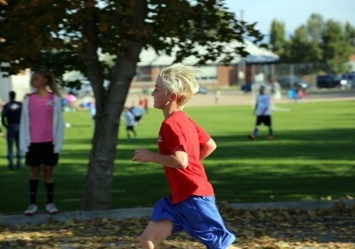 niño rubio corriendo en un parque
