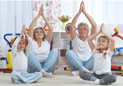  Grupo de niñas y adultos mayores haciendo yoga en la sala