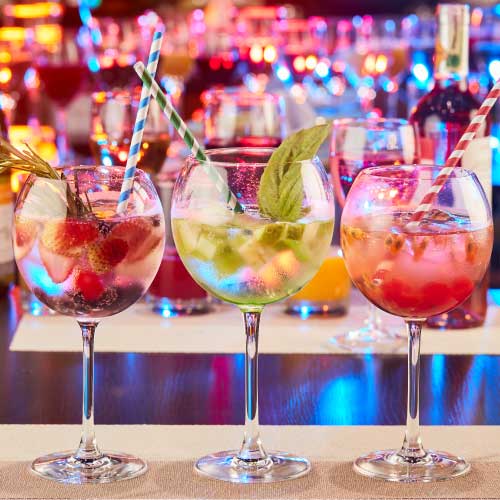 Copas con cocteles de colores decorados con frutas.