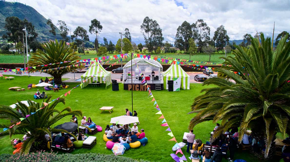 Un parque con juegos, inflables, carpas y personas disfrutando actividades al aire libre.