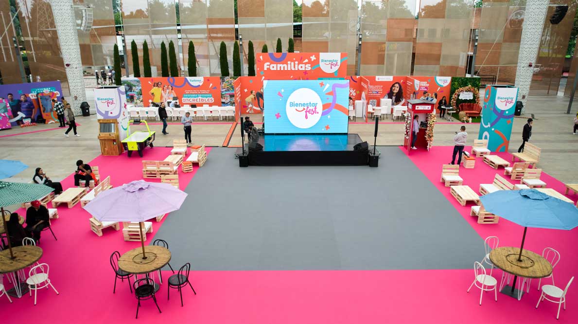Espacio de una feria con stands, pantalla gigante y zona de exhibición.