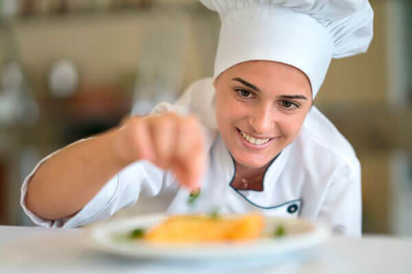 Mujer chef dando últimos toques a su plato