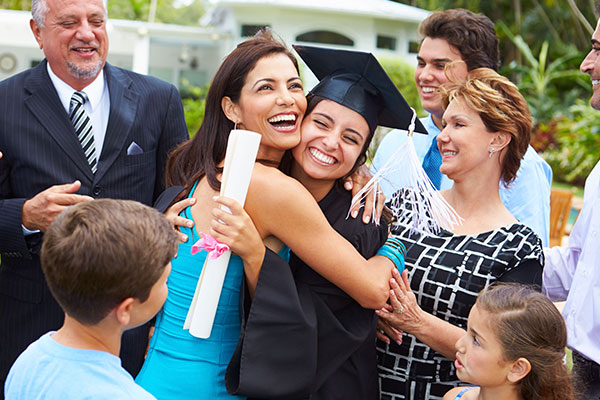 Mujer feliz abrazando a chica recíen graduada.