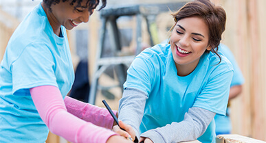mujeres sonriendo trabajando en equipo sobre unas tablas de madera.Â 