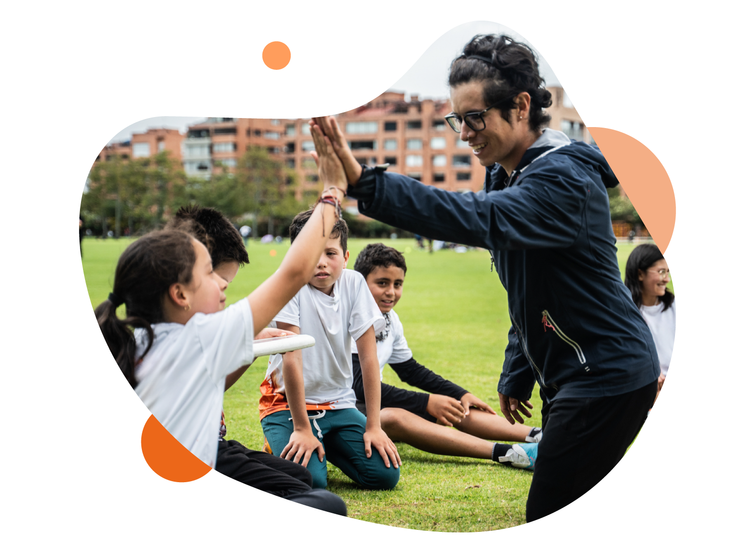  imagen de un grupo de niños en un ambiente deportivo. Uno de ellos, choca su mano con un adulto. 