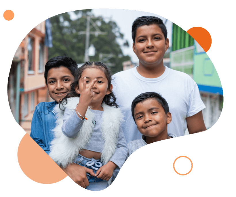 imagen de grupo de niños sonriendo y viendo al frente, una de ellas hace una señal con sus manos. 