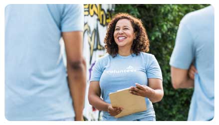 imagen de dos hombres a espaldas. Una mujer los mira fijamente sonriendo.  