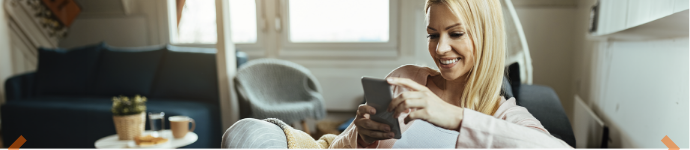 Mujer joven, sentada en un sofá, mirando su celular 