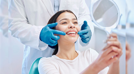 Mujer sonriendo en un espejo tras finalizar cita de odontología